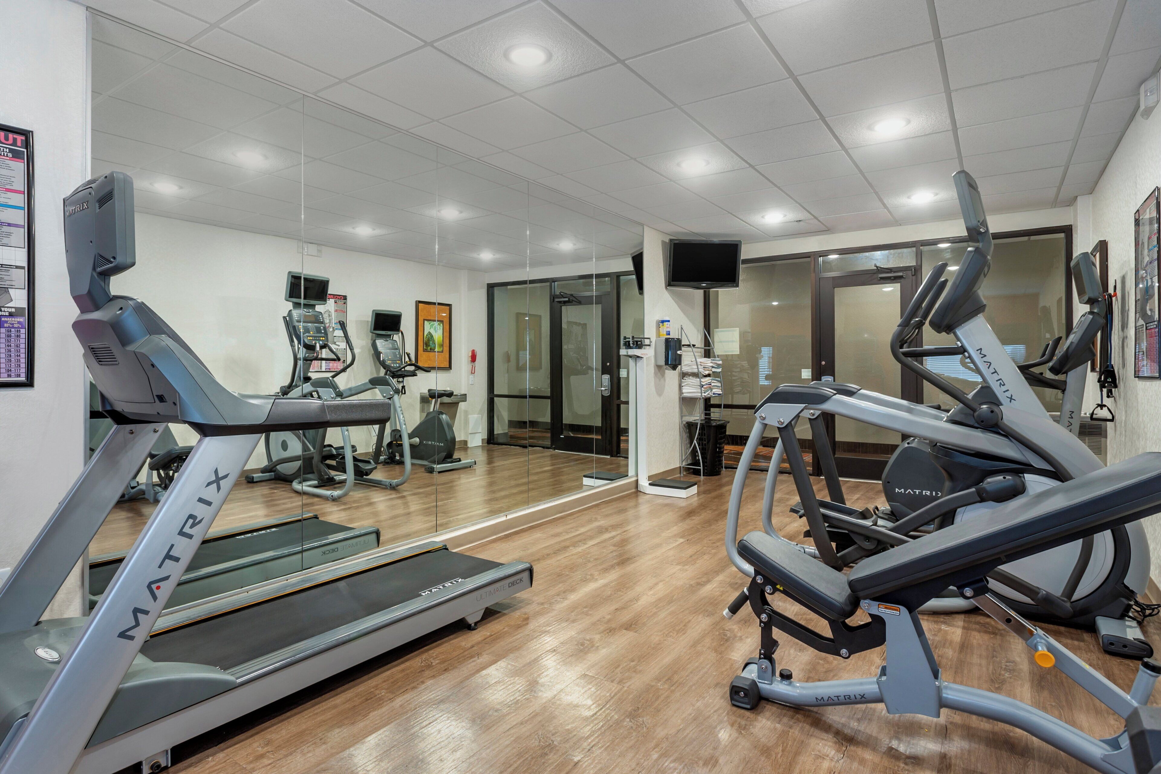 Un gimnasio con cintas de correr, elípticas y un espejo grande.