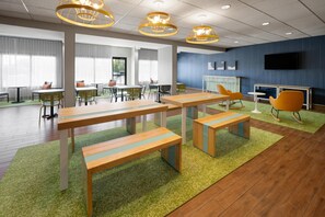A modern meeting room with tables, chairs, and a television screen.