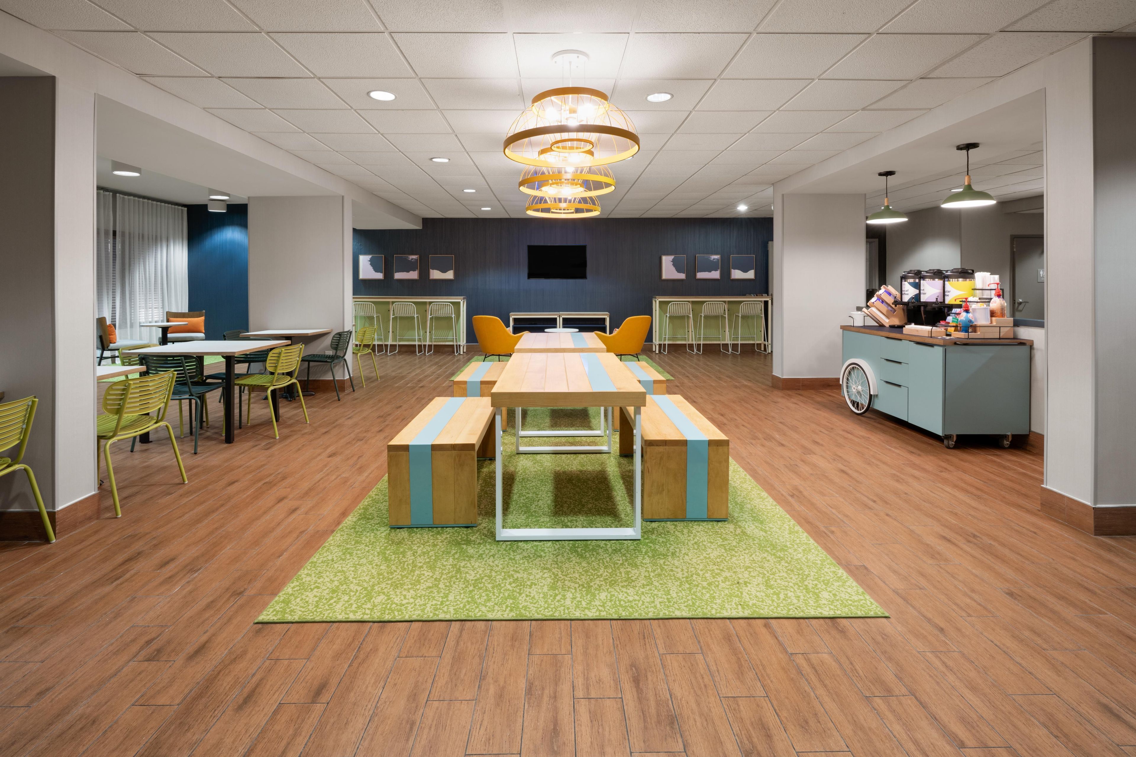 A conference room with a long table, chairs, a coffee station, and a TV screen.