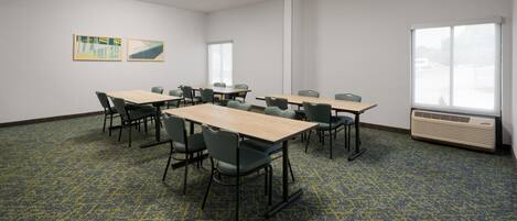 A conference room with tables and chairs, a large window, and an air conditioning unit.