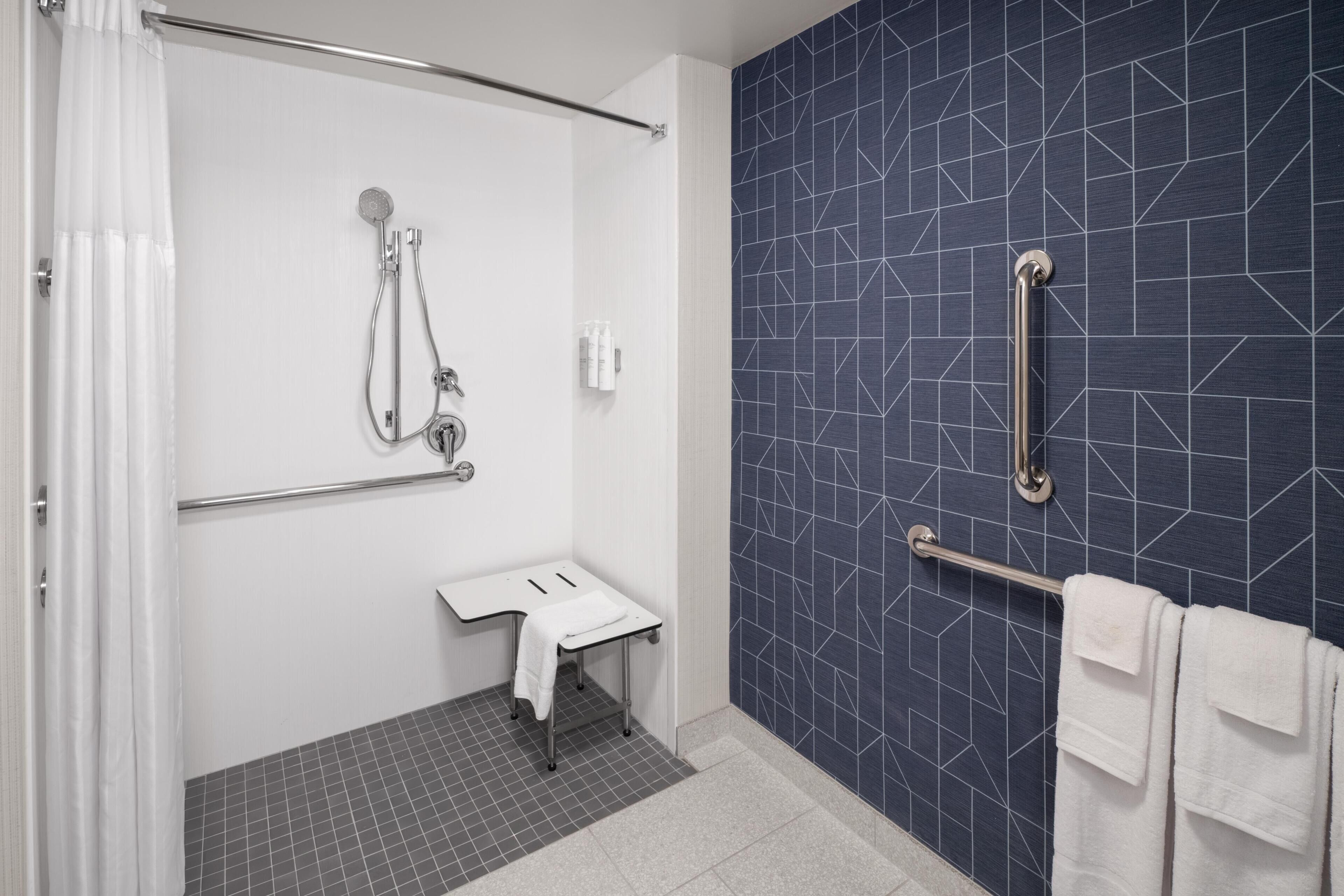 Une salle de bain moderne équipée d’une douche, d’un lavabo et d’un porte-serviettes.