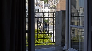 Finestra amb vista a un paisatge urbà, incloent un edifici destacat amb dues cúpules.