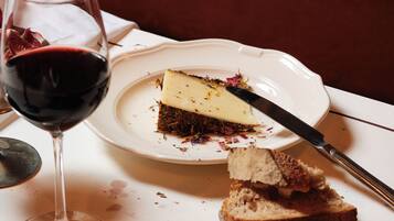 Une part de gâteau au fromage sur une assiette, avec un couteau à côté, et un verre de vin rouge.