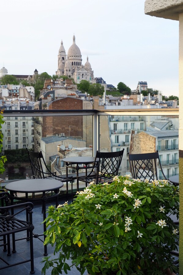 Una terraza con asientos al aire libre y vistas a un paisaje urbano que incluye edificios con cúpulas.