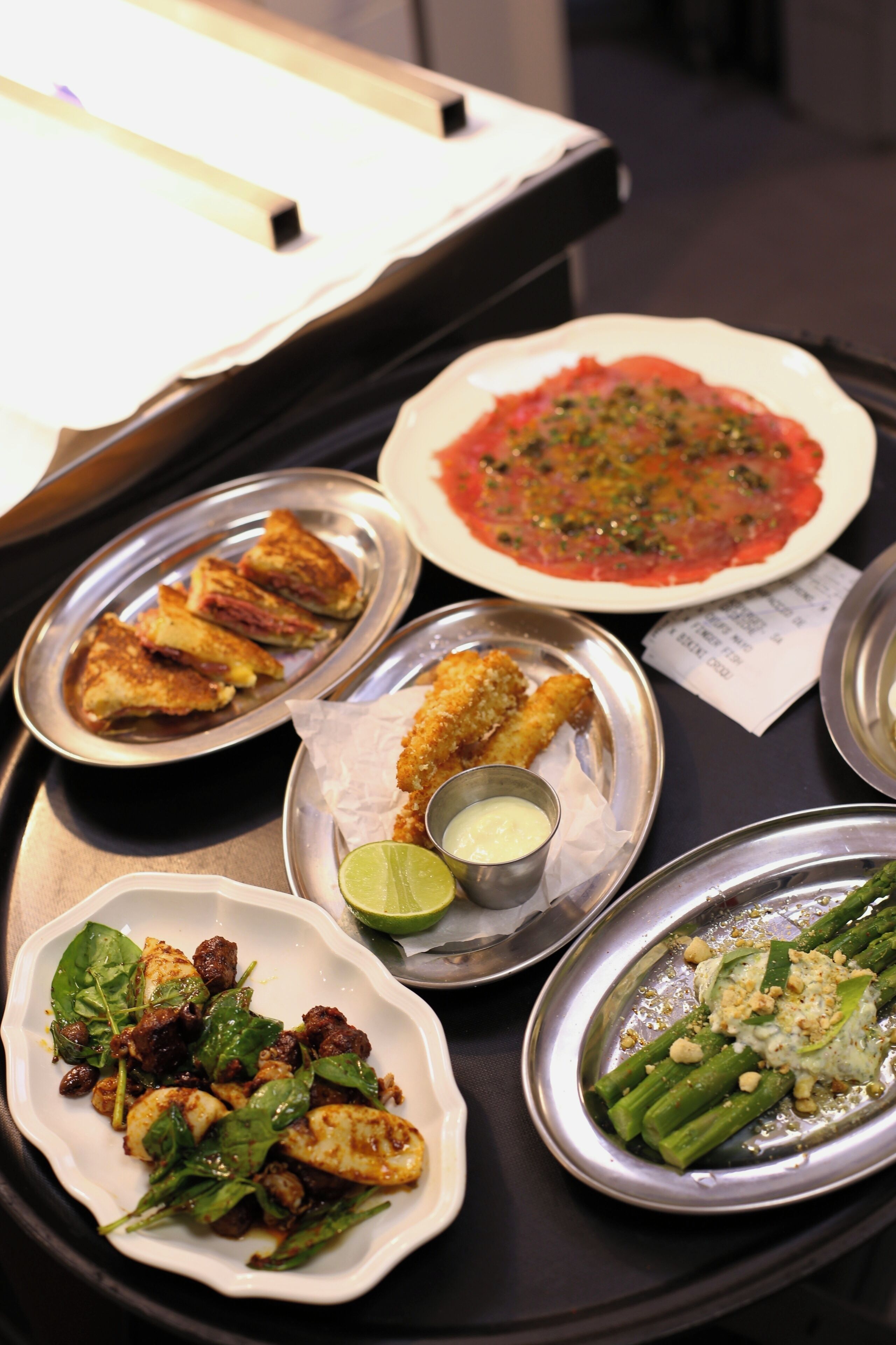 A variety of dishes on a tray, including a plate of breaded chicken, a bowl of pasta, and a dish with asparagus.