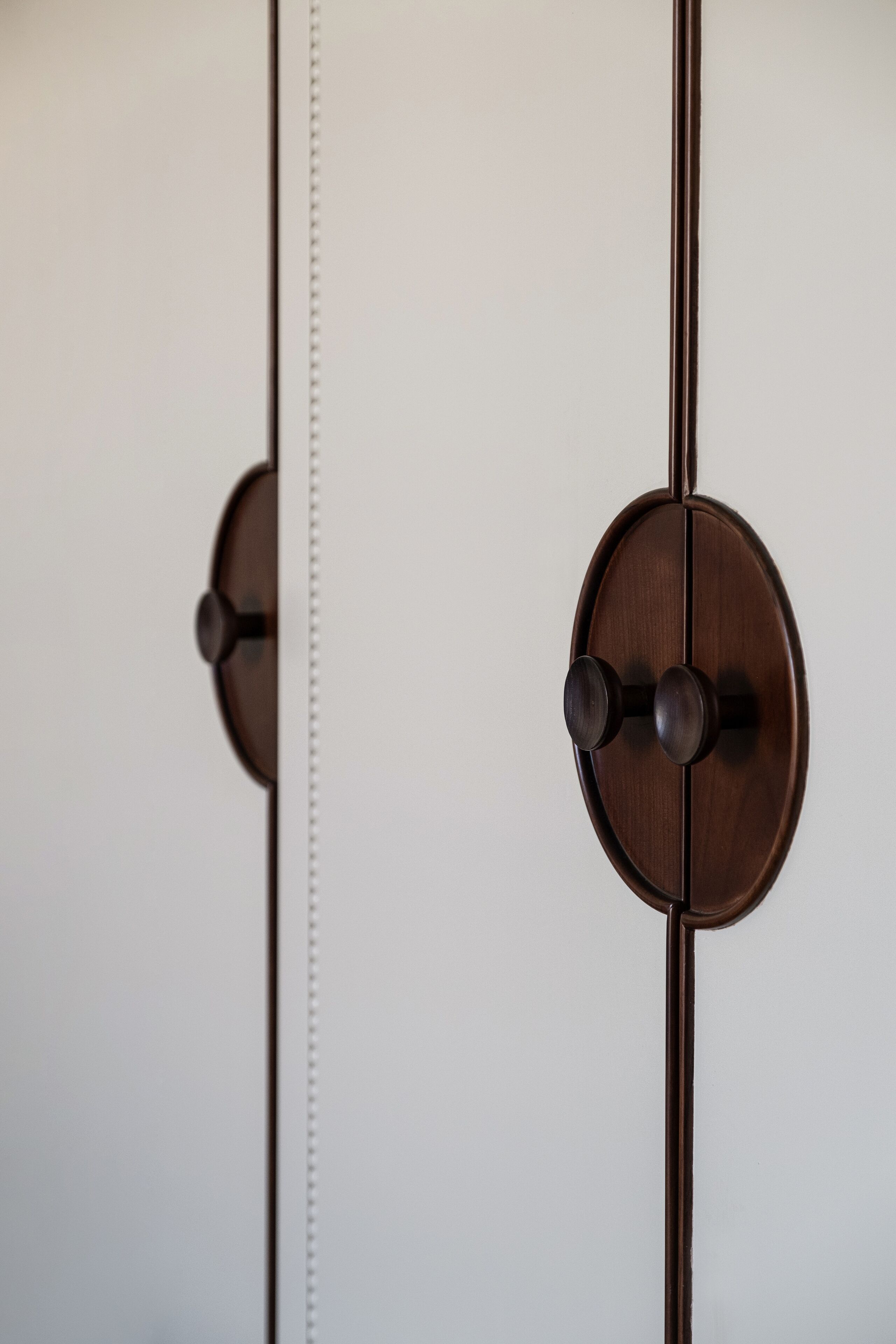 A close-up of a wooden door with a vertical handle and a mirrored surface.