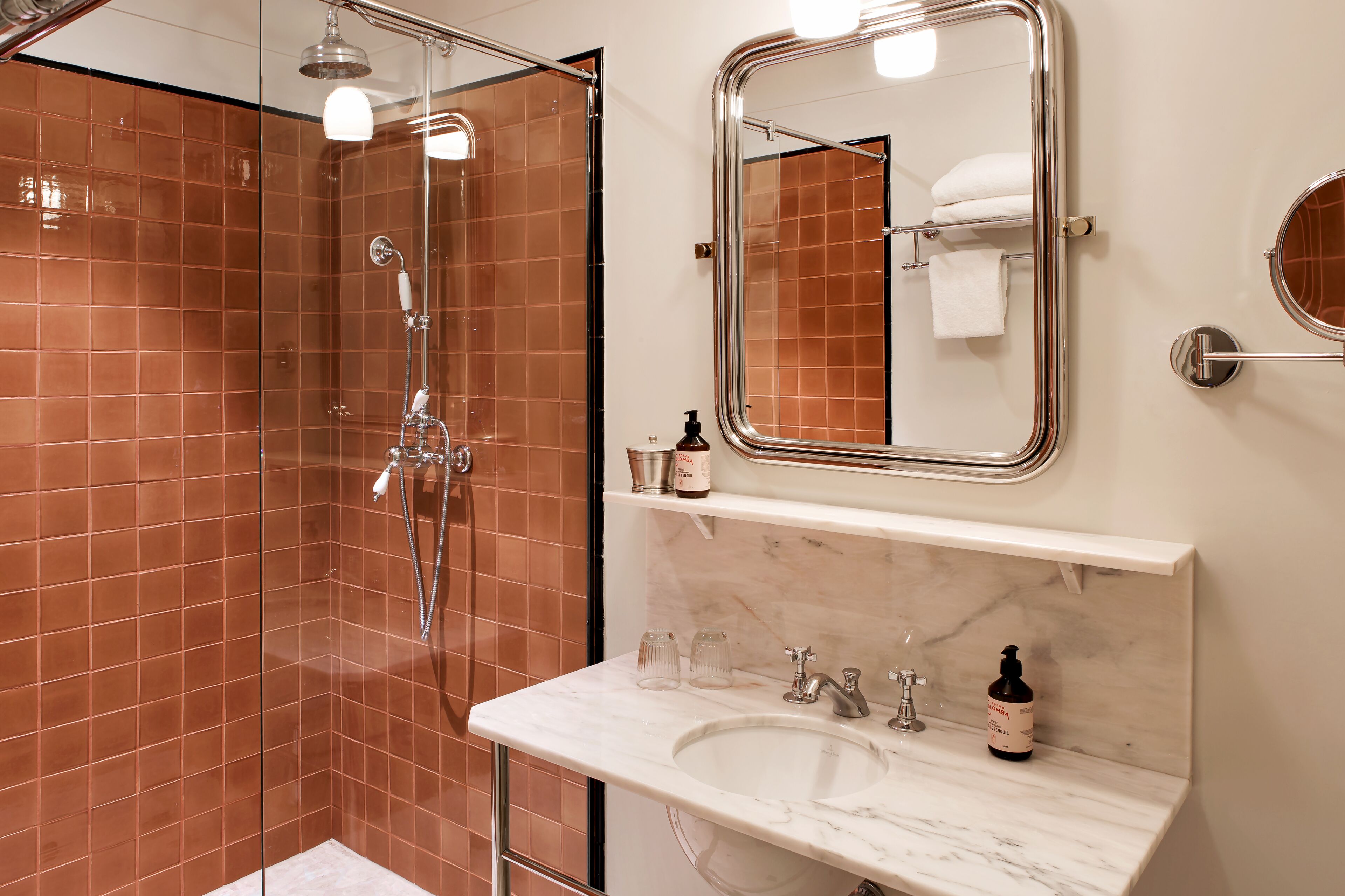 Une salle de bain avec une douche à parois de verre, un lavabo blanc et un miroir au-dessus du lavabo.