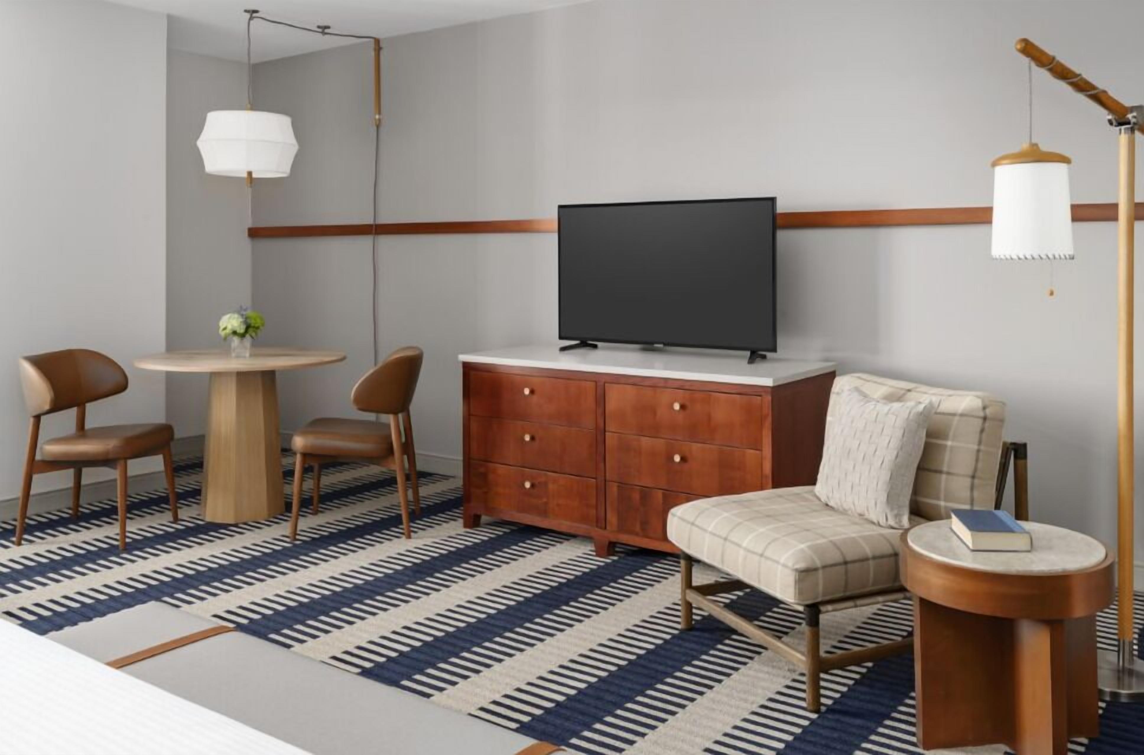A modern living room with a round table, two chairs, a sofa, a TV, and a floor lamp.