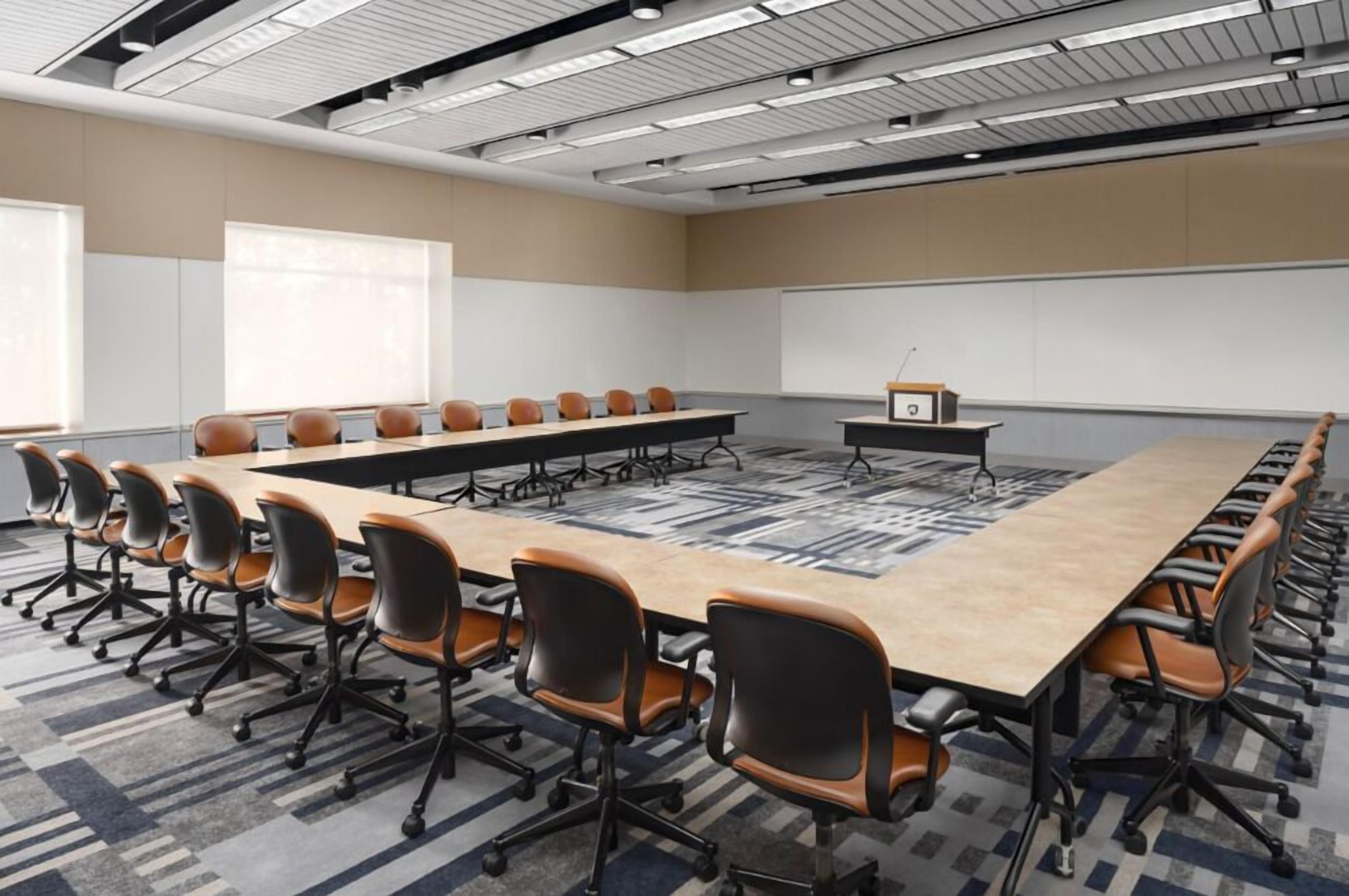 A conference room with a long table, multiple chairs, a projector, and a whiteboard.