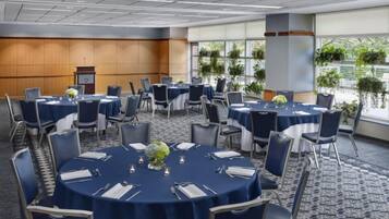 Une salle de conférence équipée de tables rondes, de chaises et d’un pupitre.