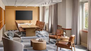 A conference room with a large table, chairs, a television, and a patterned carpet.