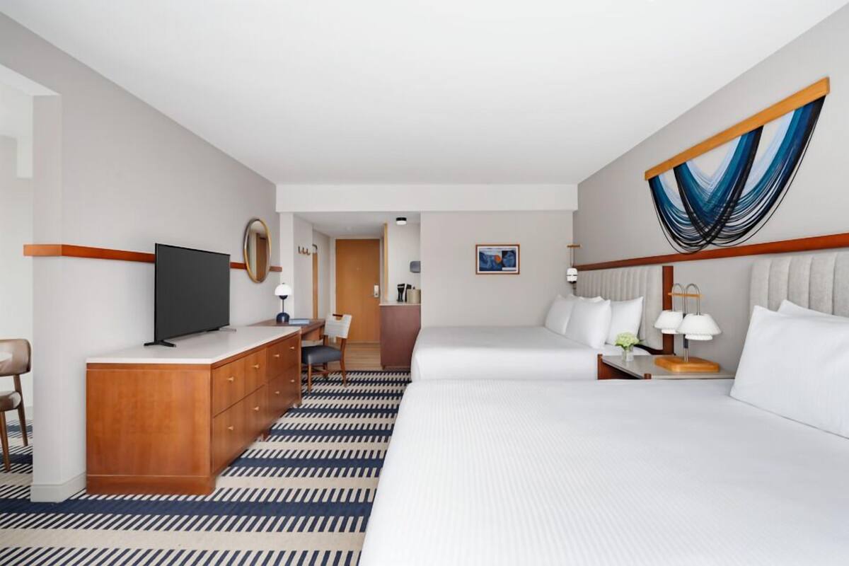 A hotel room with a large bed, a desk with a chair, a television, and a bathroom visible through an open door.