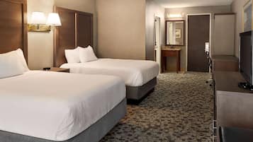 Habitación de hotel con dos camas, un escritorio, televisión, baño y piso alfombrado.