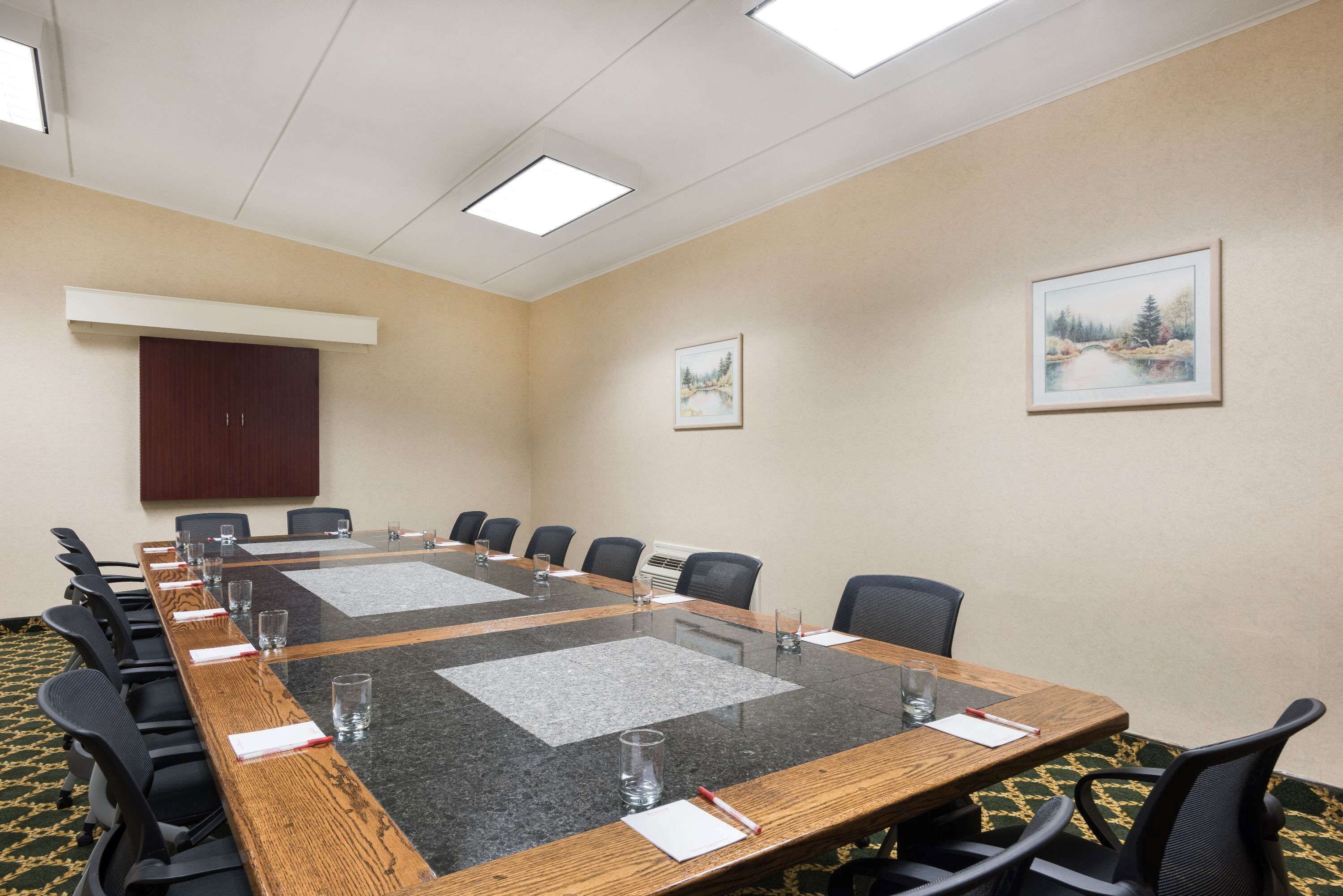 Un salón de conferencias con una mesa larga, sillas y un armario.