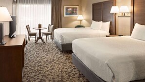 A hotel room with two beds, a desk, a chair, a lamp, and a painting on the wall. - Ramada Plaza by Wyndham Portland (Portland)
