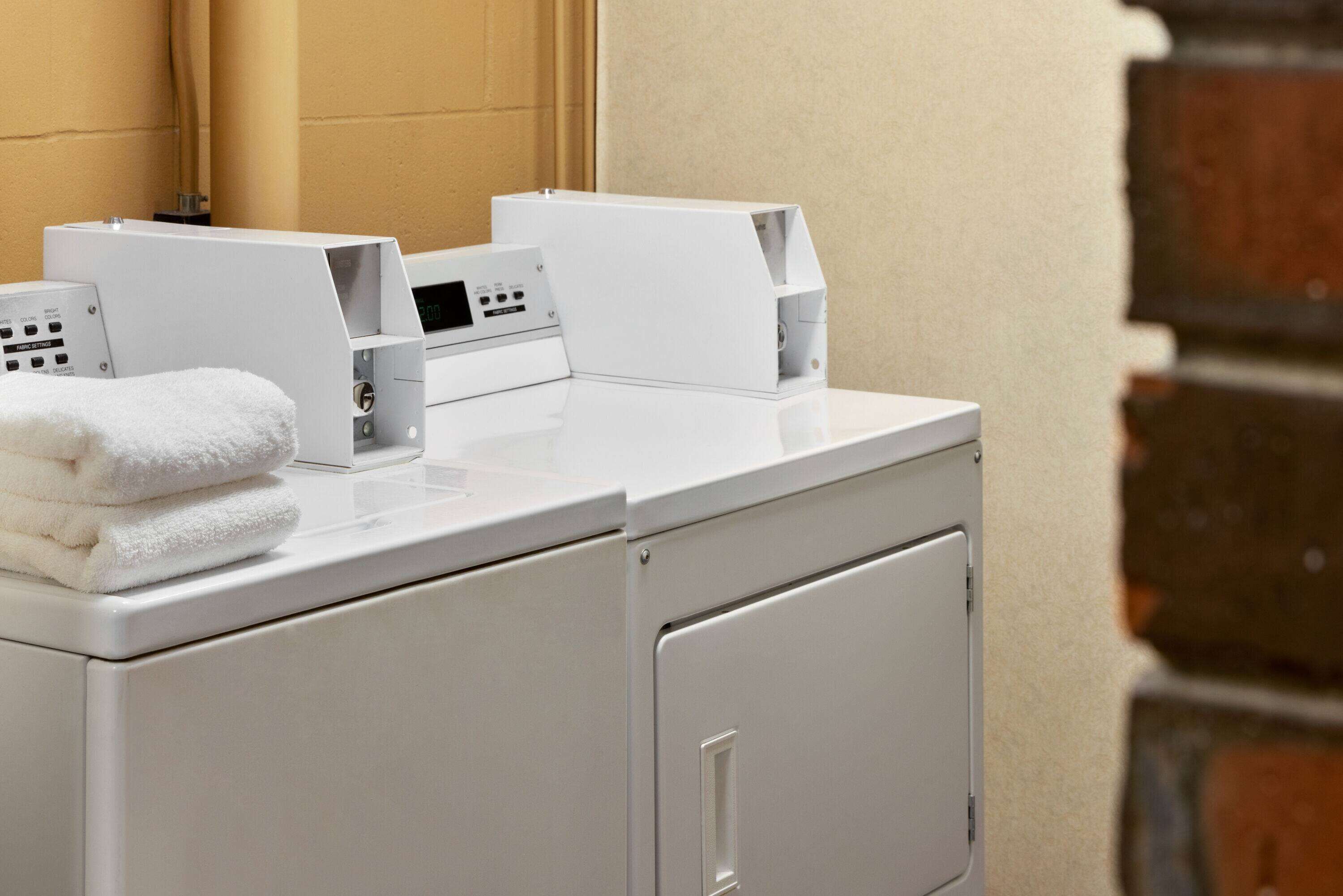 A modern laundry area with stacked towels, a washing machine, and a dryer.
