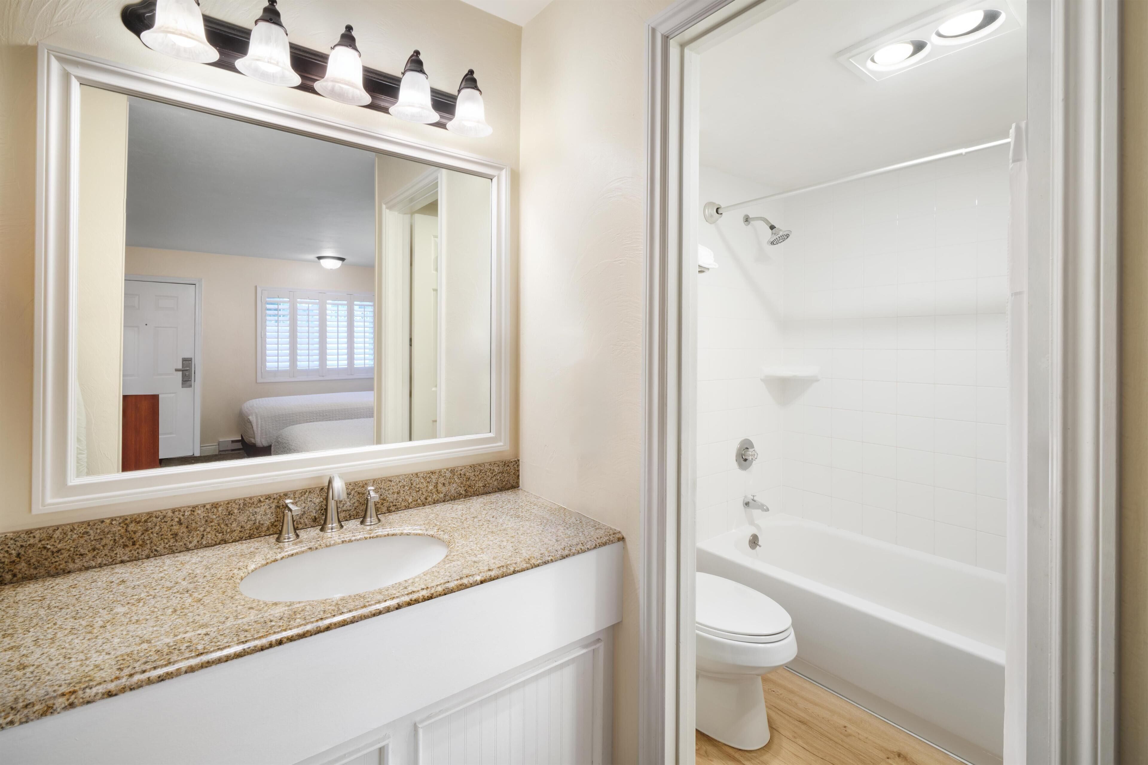 A bathroom with a double sink vanity, a large mirror, a toilet, and a walk-in shower.