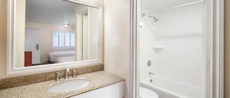 A bathroom with a double sink vanity, a large mirror, a toilet, and a walk-in shower.