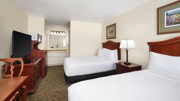 A hotel room with two beds, a television, a desk, and a dresser.