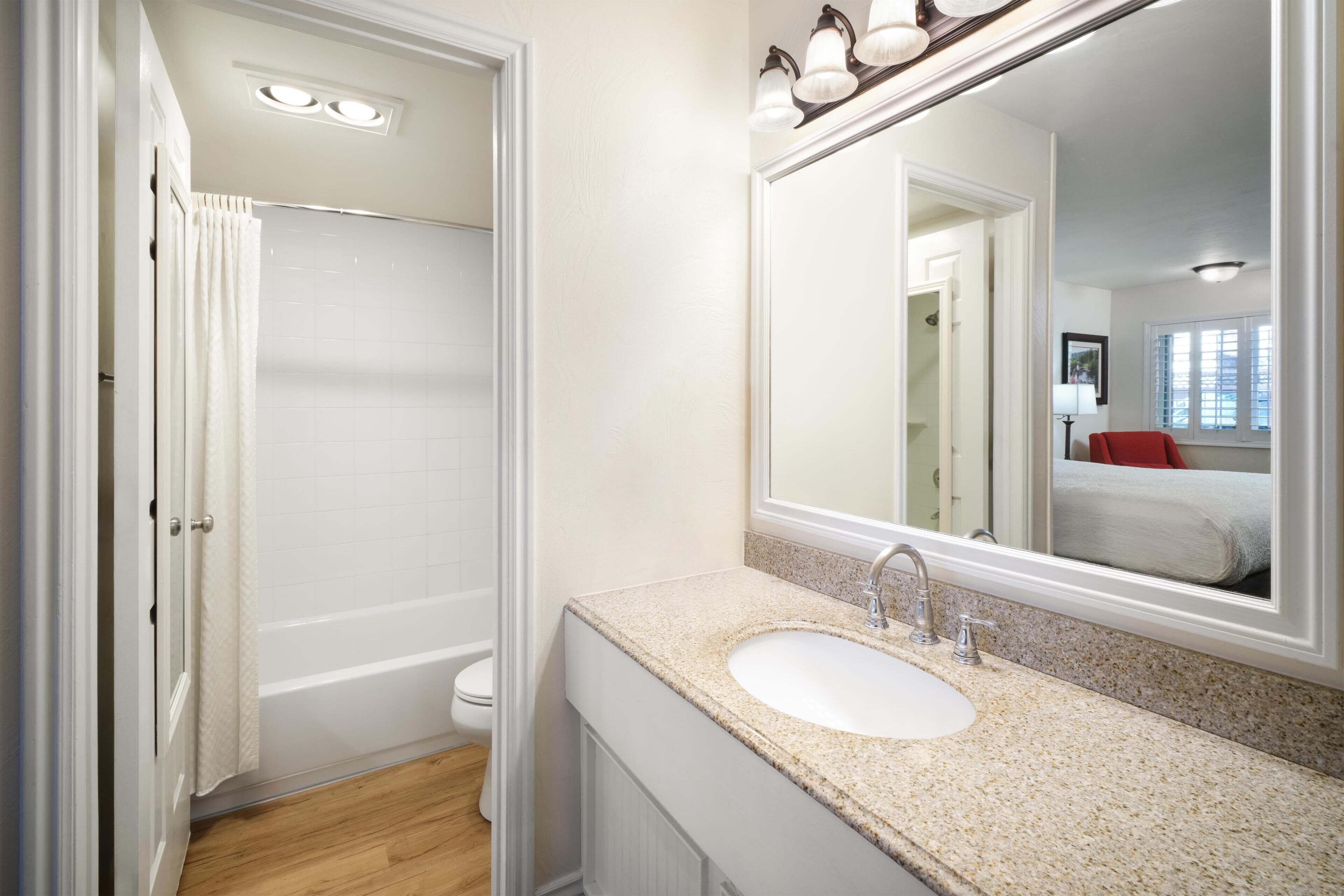 A bathroom with a white sink, a mirror, and a shower.