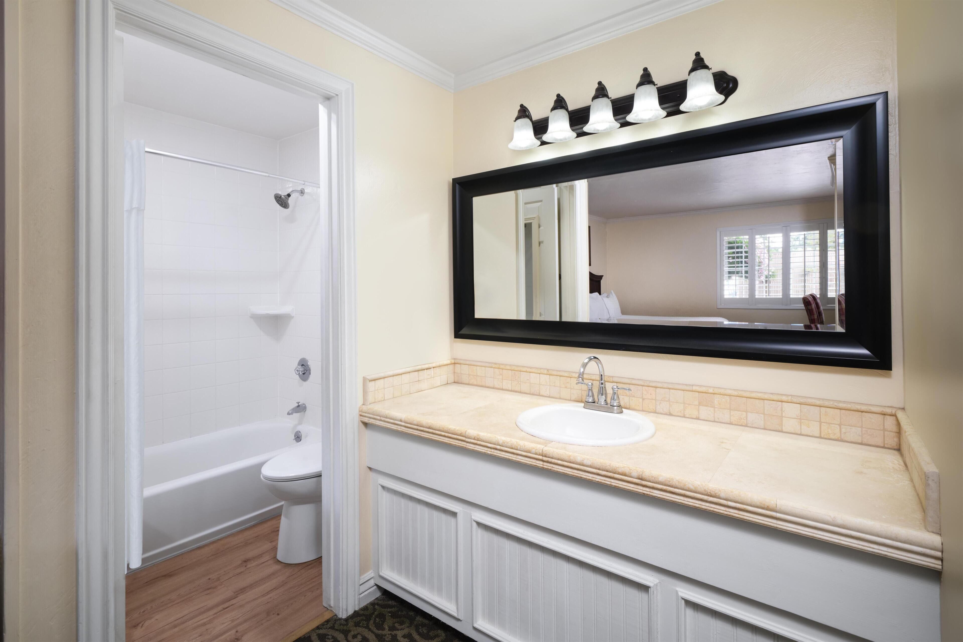 A bathroom with a white bathtub, a sink with a mirror above it, and a shower curtain.