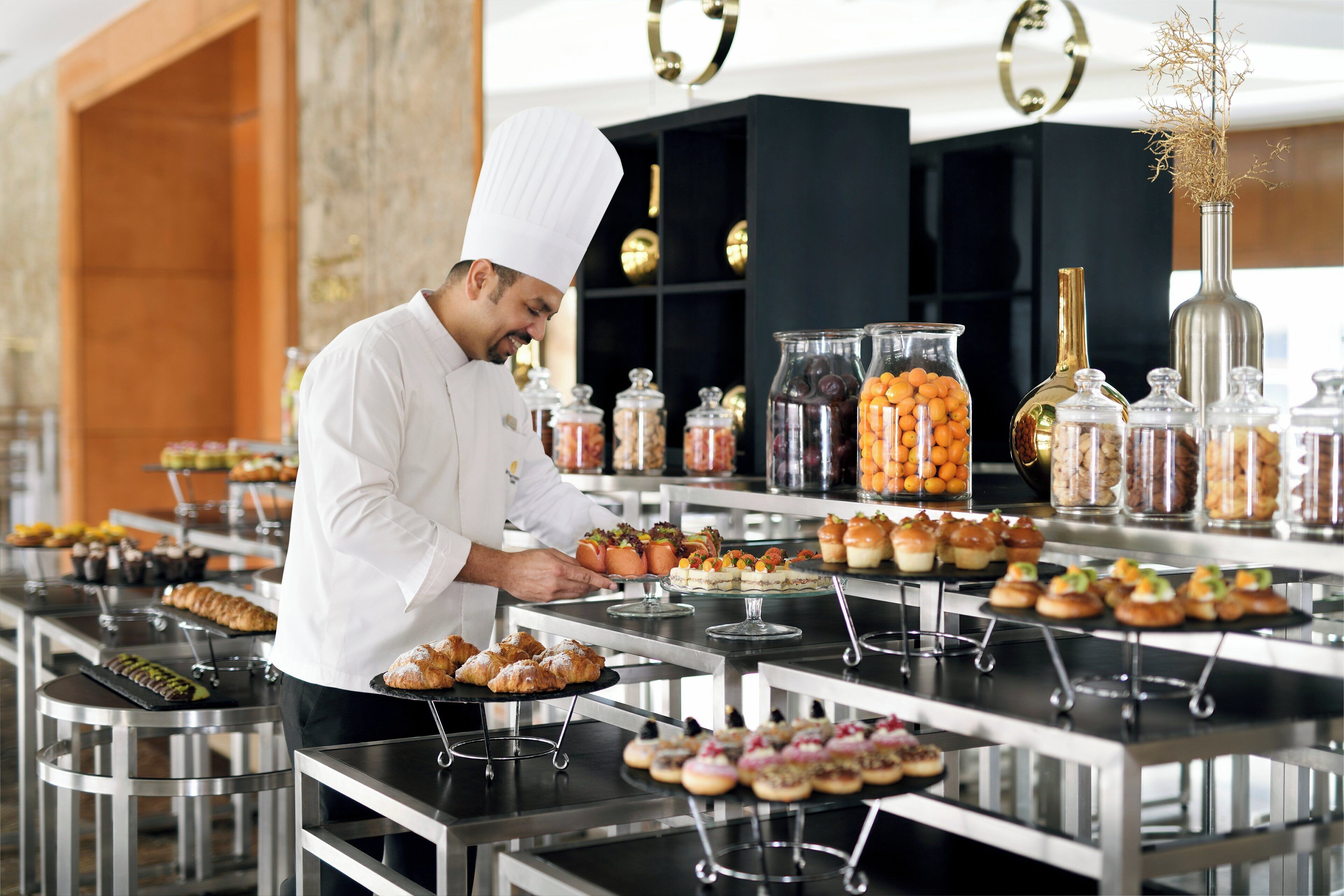 Un chef en una cocina profesional con diversos alimentos y condimentos expuestos sobre mesas.