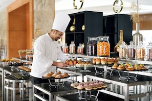Un xef en una cuina professional, amb diferents aliments i condiments presents sobre taules.