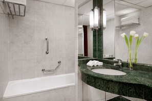 A modern bathroom with a bathtub, a sink, and a mirror.