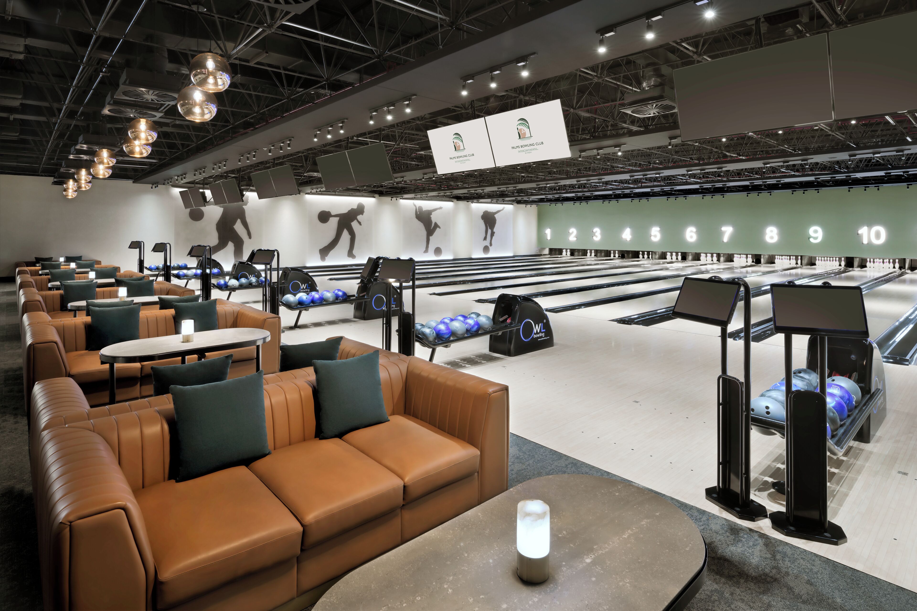 A bowling alley with seating areas, bowling lanes, and overhead signage.
