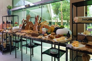 A buffet table with various cheeses, breads, and a bottle of balsamic vinegar. - InterContinental Riyadh by IHG (Riyadh)