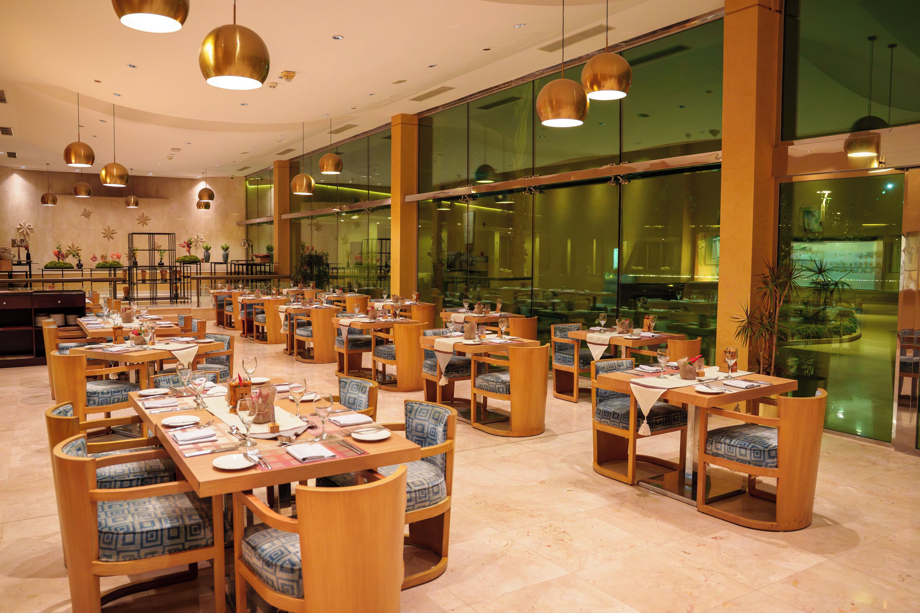 Un'ampia sala ristorante con numerosi tavoli e sedie, ampie finestre e luci a sospensione.