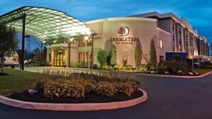 A hotel with a large glass canopy entrance, a well-maintained garden, and a sign indicating it is a DoubleTree by Hilton property. - DoubleTree by Hilton Hotel Buffalo - Amherst (Buffalo)