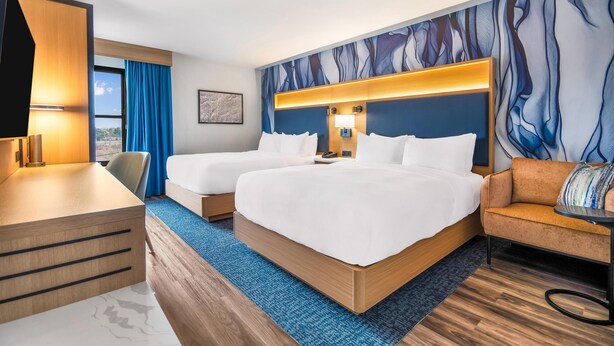 A hotel room with two beds, a desk, a sofa, and a large abstract mural on the wall. - DoubleTree by Hilton Hotel Buffalo - Amherst (Buffalo)