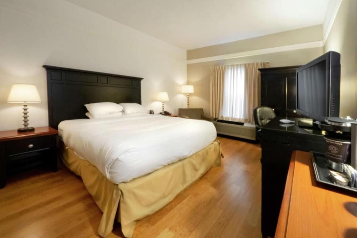 A hotel room with a large bed, bedside lamps, a desk with a television, and a coffee maker.