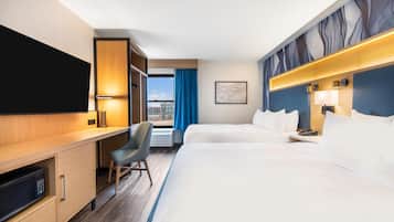 A hotel room with a bed, a desk, a chair, a TV, and a window with curtains.