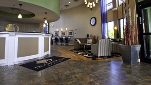 A lobby with a reception desk, seating area, and a clock on the wall. - DoubleTree by Hilton Hotel Buffalo - Amherst (Buffalo)
