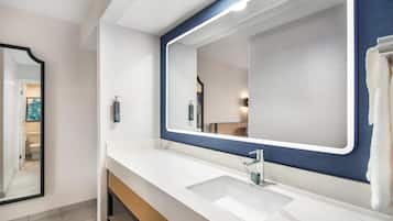 A bathroom with a white sink, a large mirror with a blue frame, and a towel hanging on the wall.