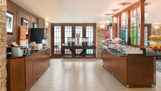 A spacious kitchen with wooden cabinets, a central island, and a stone accent wall.