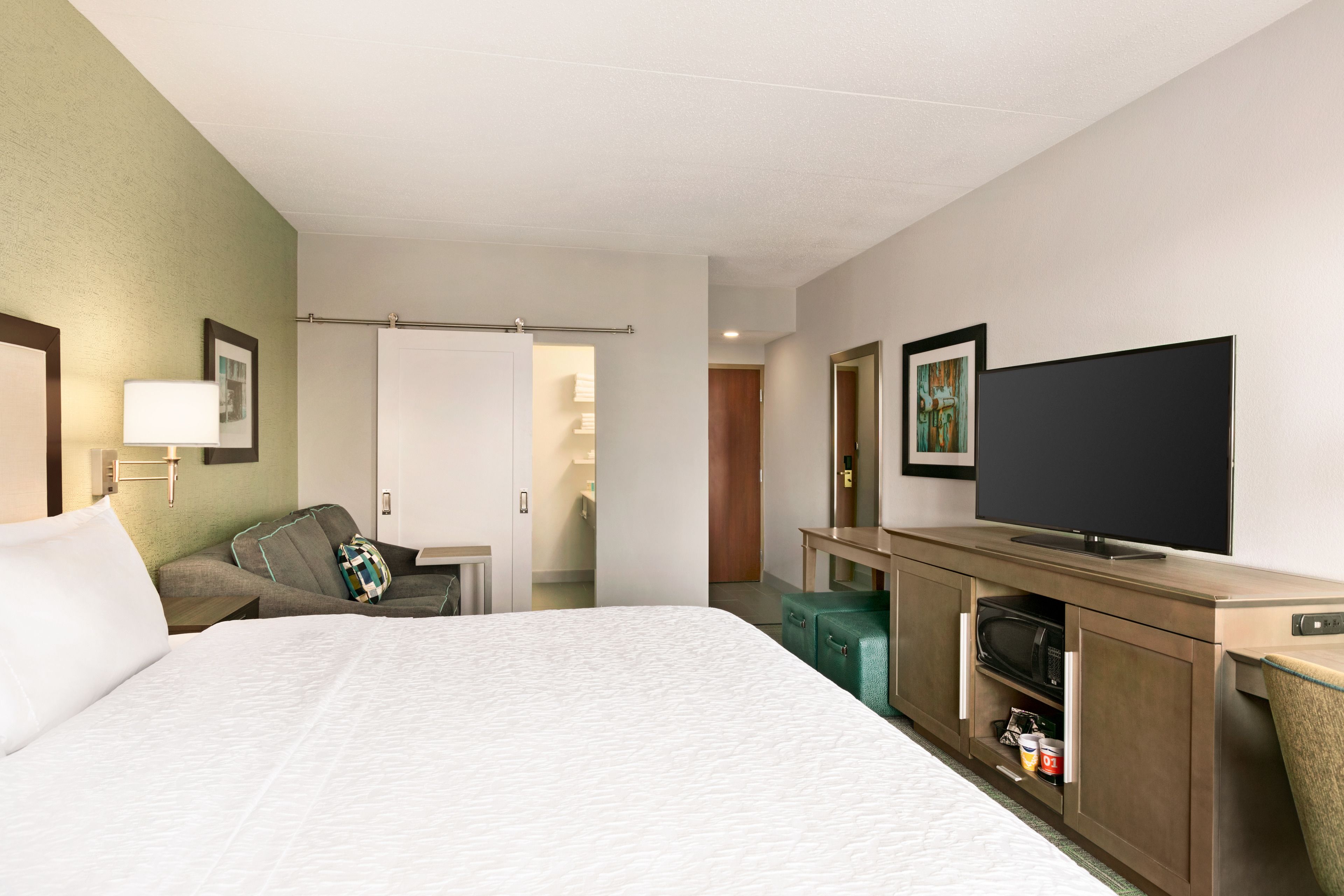 Een hotelkamer met een bed, een televisie, een magnetron en een klein tafeltje.