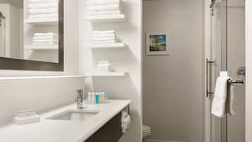A modern bathroom with a white sink, mirror, and shelves with folded towels.