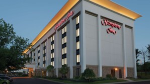 A Hampton Inn hotel building with a modern design, featuring a prominent sign and multiple windows.