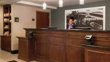 A reception desk with a wooden finish, a digital kiosk, and a large poster advertising 'explore.'
