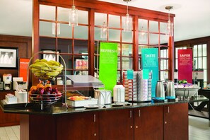 A buffet area with a fruit bowl, beverage dispensers, and a coffee station.