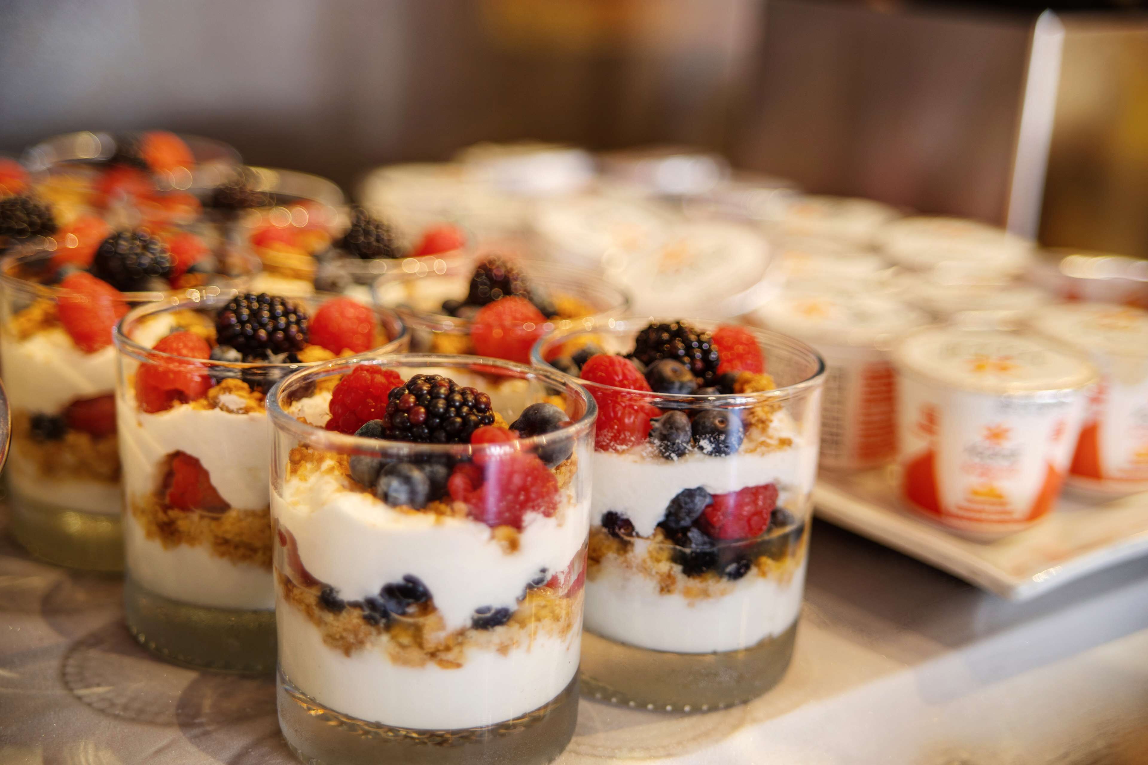 A dessert tray with layered parfaits topped with berries and granola.