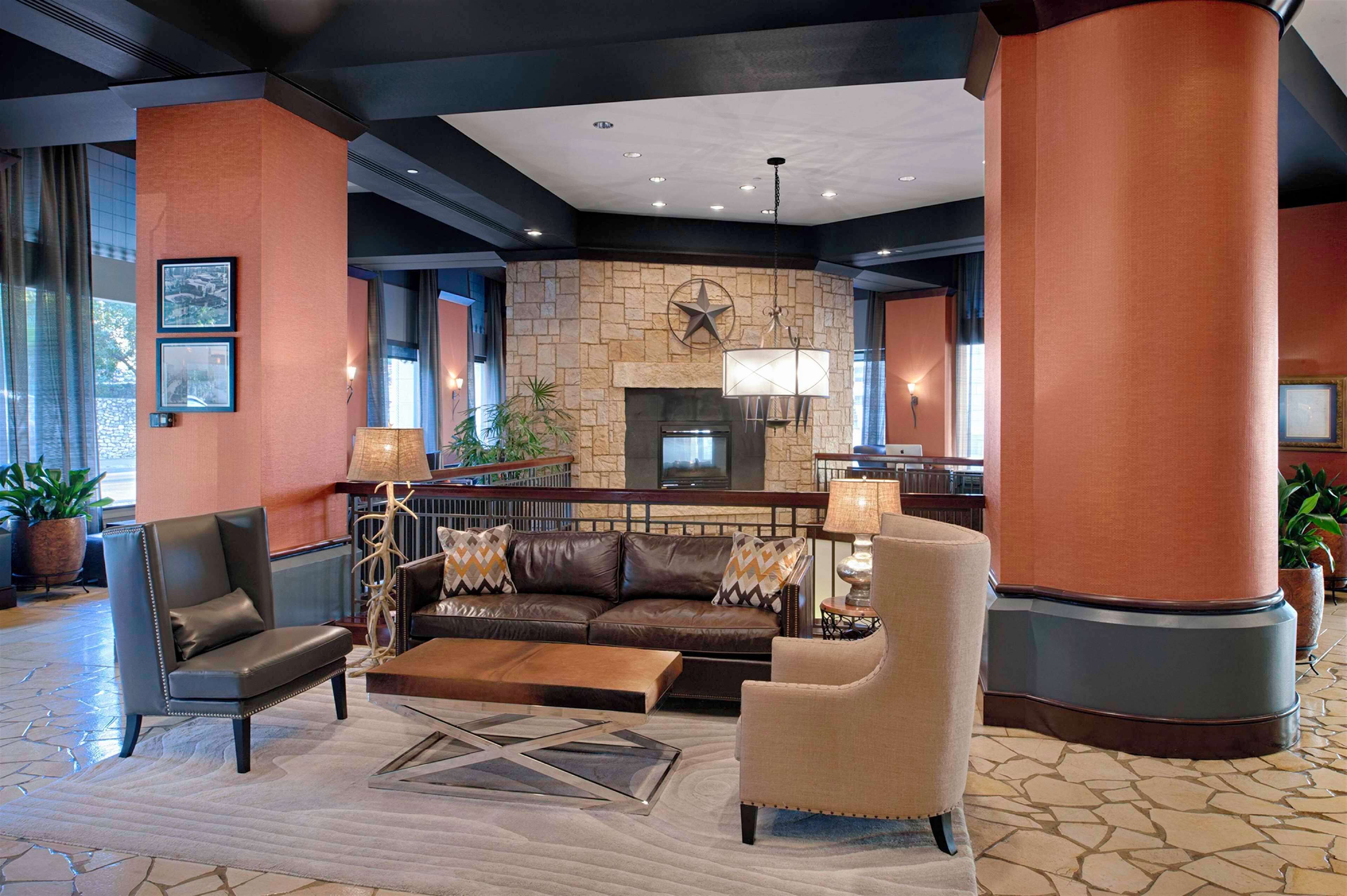 A lobby with a stone fireplace, leather sofas, and a large pillar.