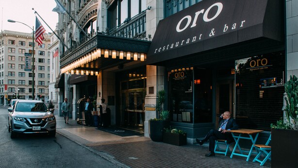 Un restaurante llamado 'oro' con una fachada arquitectónica clásica, una entrada visible y una zona de estar al aire libre.