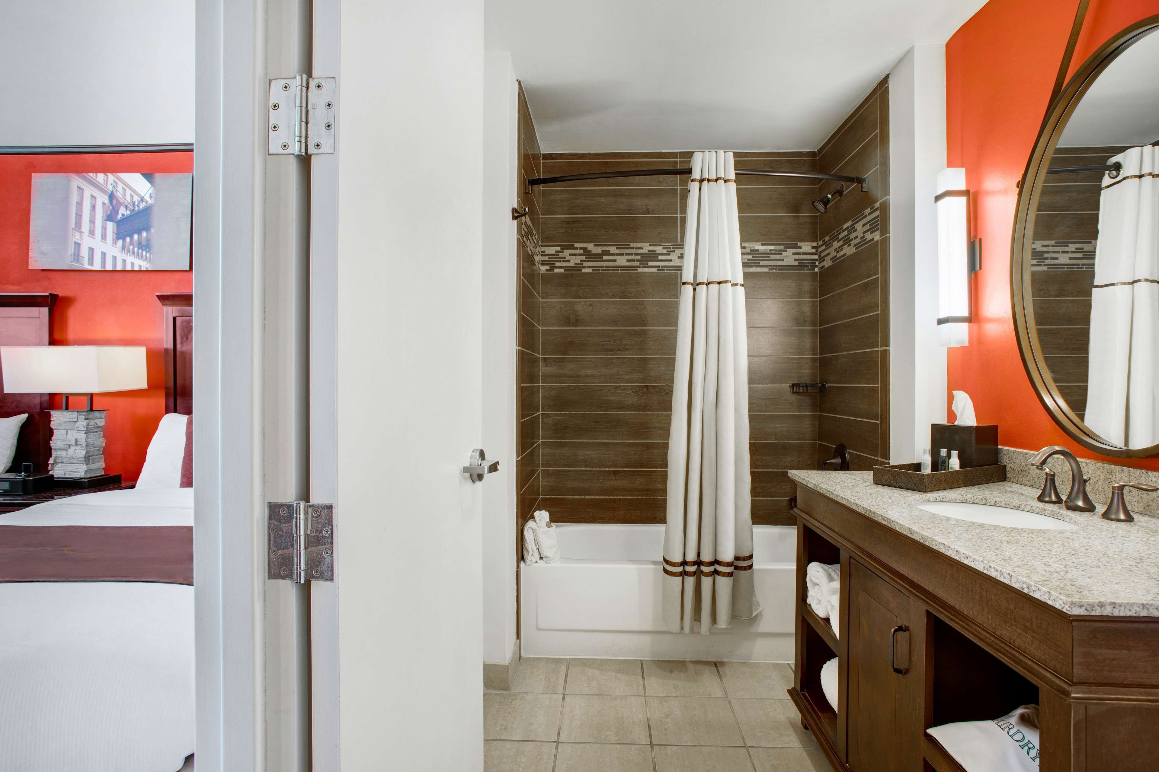 A modern bathroom with a bathtub, shower, and a large mirror.