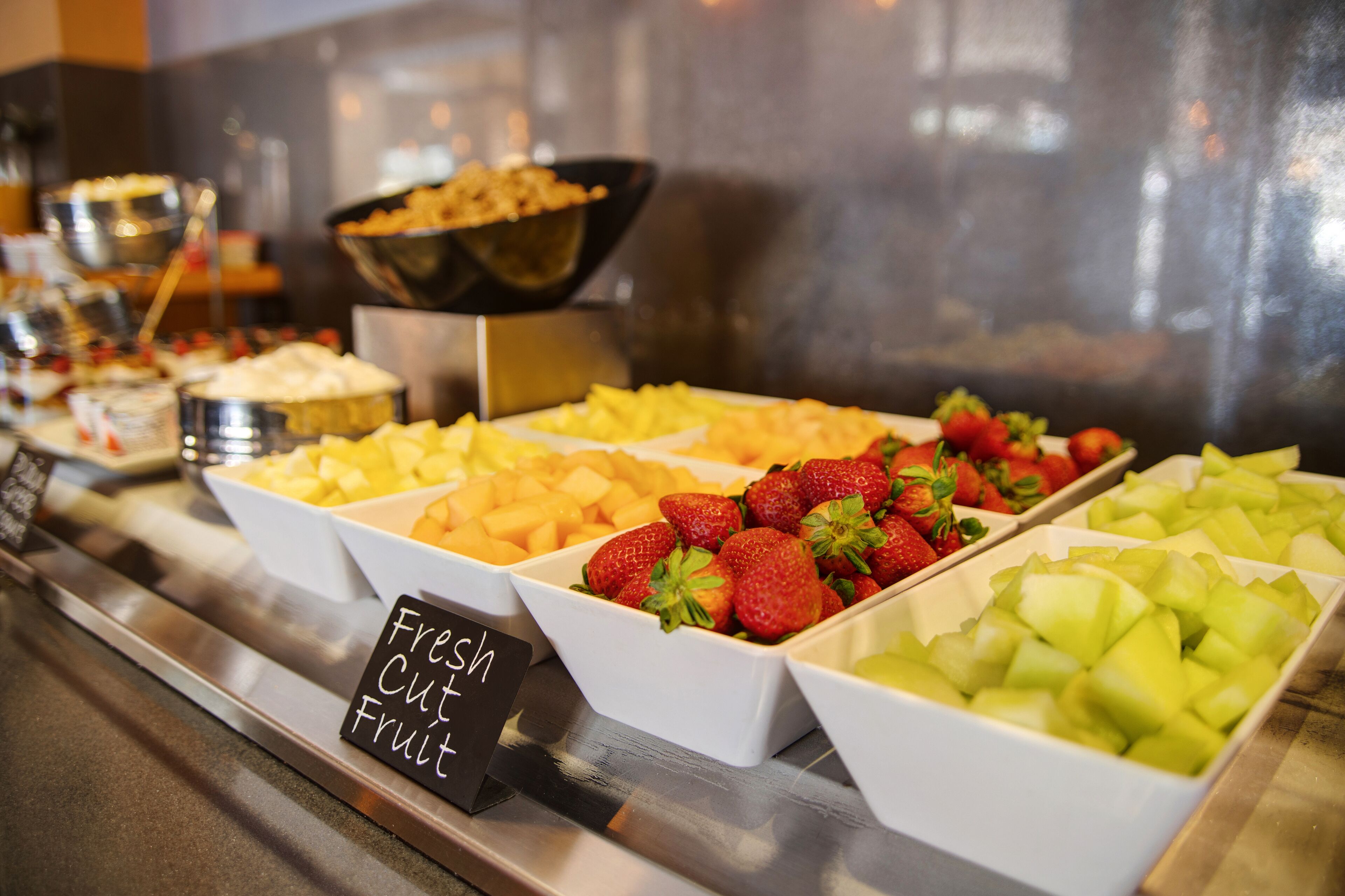 A buffet with various fresh fruits including strawberries, cantaloupe, and melon.