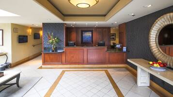 A reception area with a wooden reception desk, a large mirror, and a bench with a fruit bowl.