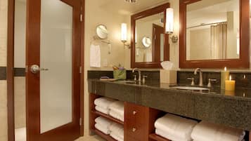 Un baño con tocador de madera, lavamanos, espejo y toallero.